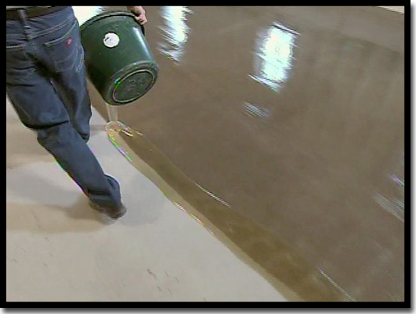 A Concrete Renewal technician pouring LABPOX 30, a 100% solids industrial-grade epoxy base coat, onto prepared concrete to ensure the resin wets deep into the pores for a permanent bond in a Twin Cities garage.