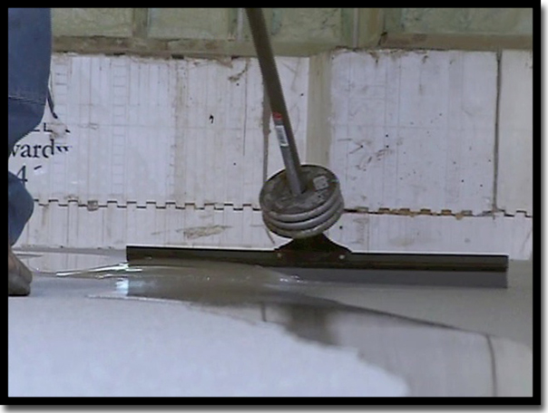 Spreading the LABFAST LO 85 UV-stable polyaspartic top coat with a weighted squeegee to ensure uniform thickness and a perfect seal over the Poly-Quartz armor layer in a Twin Cities garage.