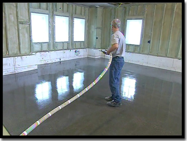 Concrete Renewal owner Greg Richard using a specialized blower to broadcast rigid quartz aggregate into the liquid epoxy base coat. This 'Quartz Suit of Armor' creates a 100+ mil thick protective layer that is nearly ten times thicker than standard paint chip flake floors in Twin Cities garages.