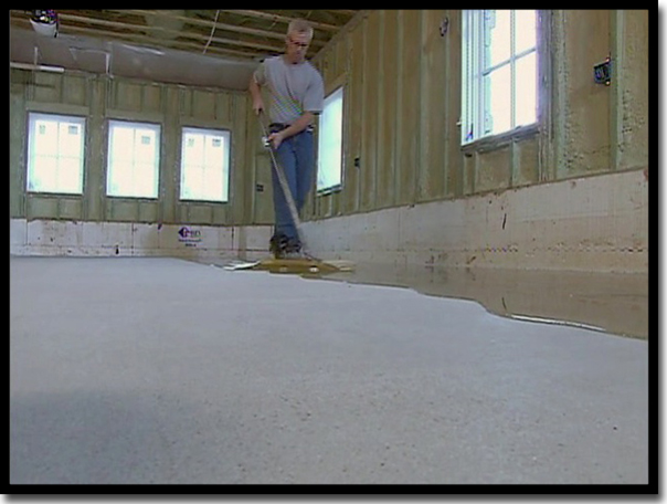 Concrete Renewal owner Greg Richard spreading the LABPOX 30 industrial-grade epoxy base coat across a Twin Cities garage floor. This 100% solids epoxy is designed to wet deep into concrete pores, creating a massive 13,000 psi compressive strength mechanical bond that outperforms standard 'one-day' polyurea primers.