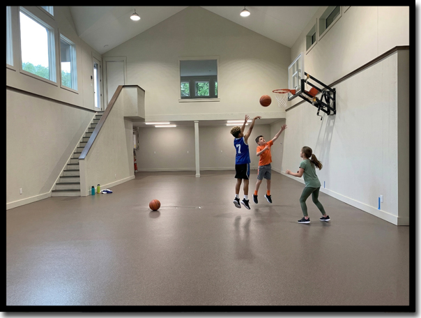 Indoor basketball court and playroom in a Stillwater, MN home featuring a master-crafted Poly-Quartz floor coating from Concrete Renewal. This durable, no-slip surface transforms garage spaces into safe, active living areas with a high-traction finish that maintains a superior 0.75 – 0.85 Wet DCOF, well exceeding the ANSI safety standard of 0.42.